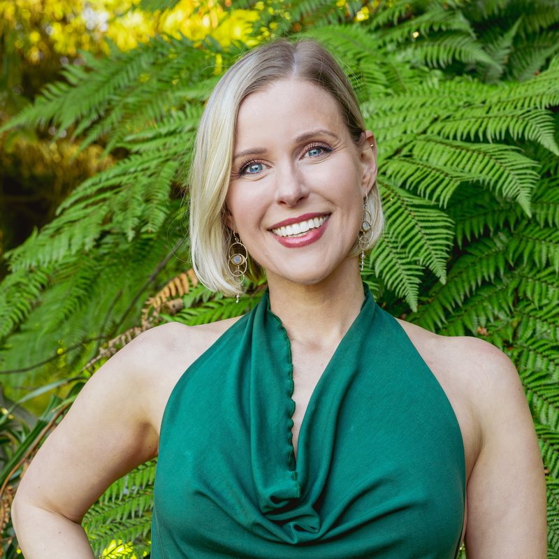 Caitlin Ryan, vinyasa yoga teacher at The Castro Room in San Francisco, smiling in a green halter top in front of ferns